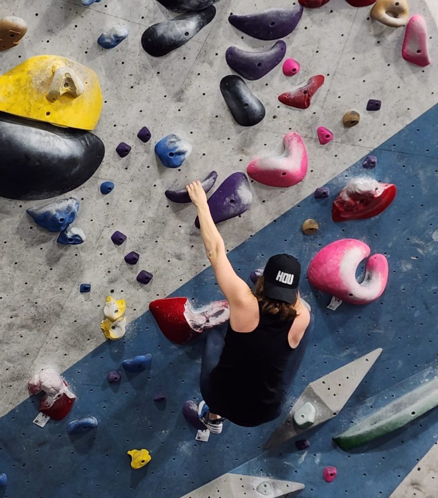 A woman in black rock climbing.