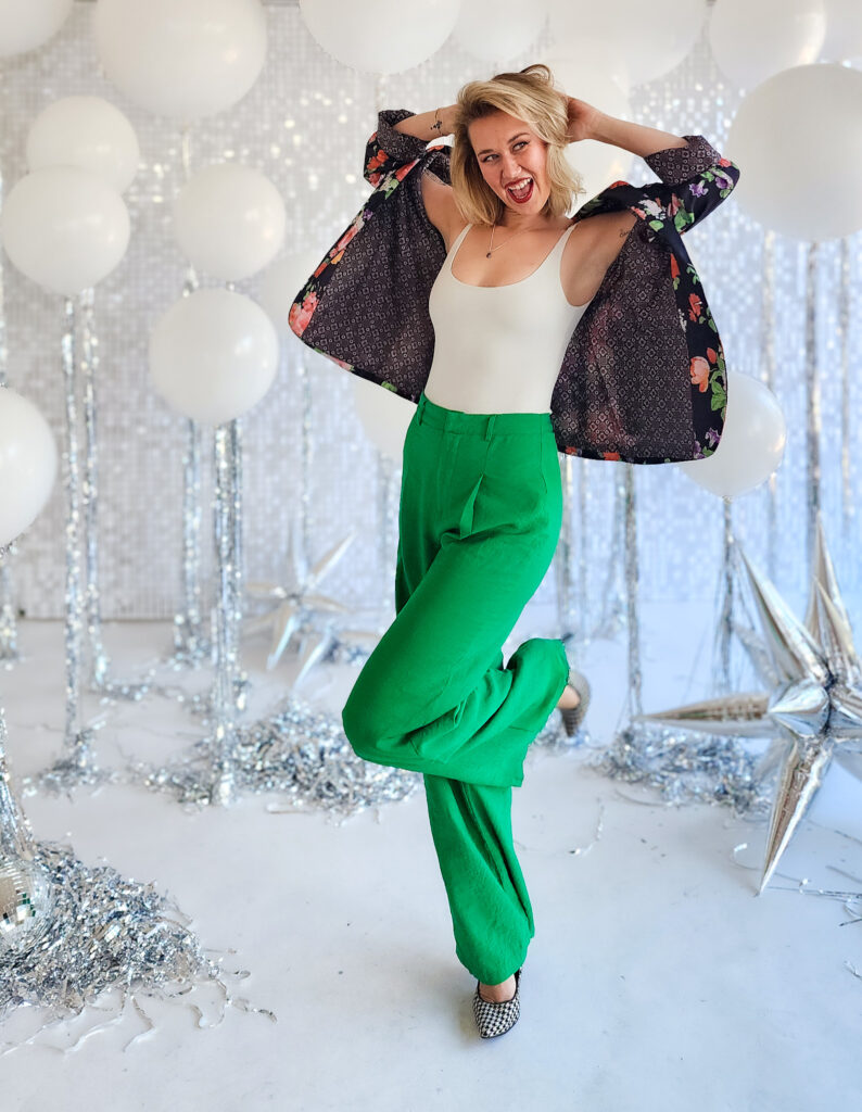 Woman dressed up and smiling in the middle of white balloons and sequins. 